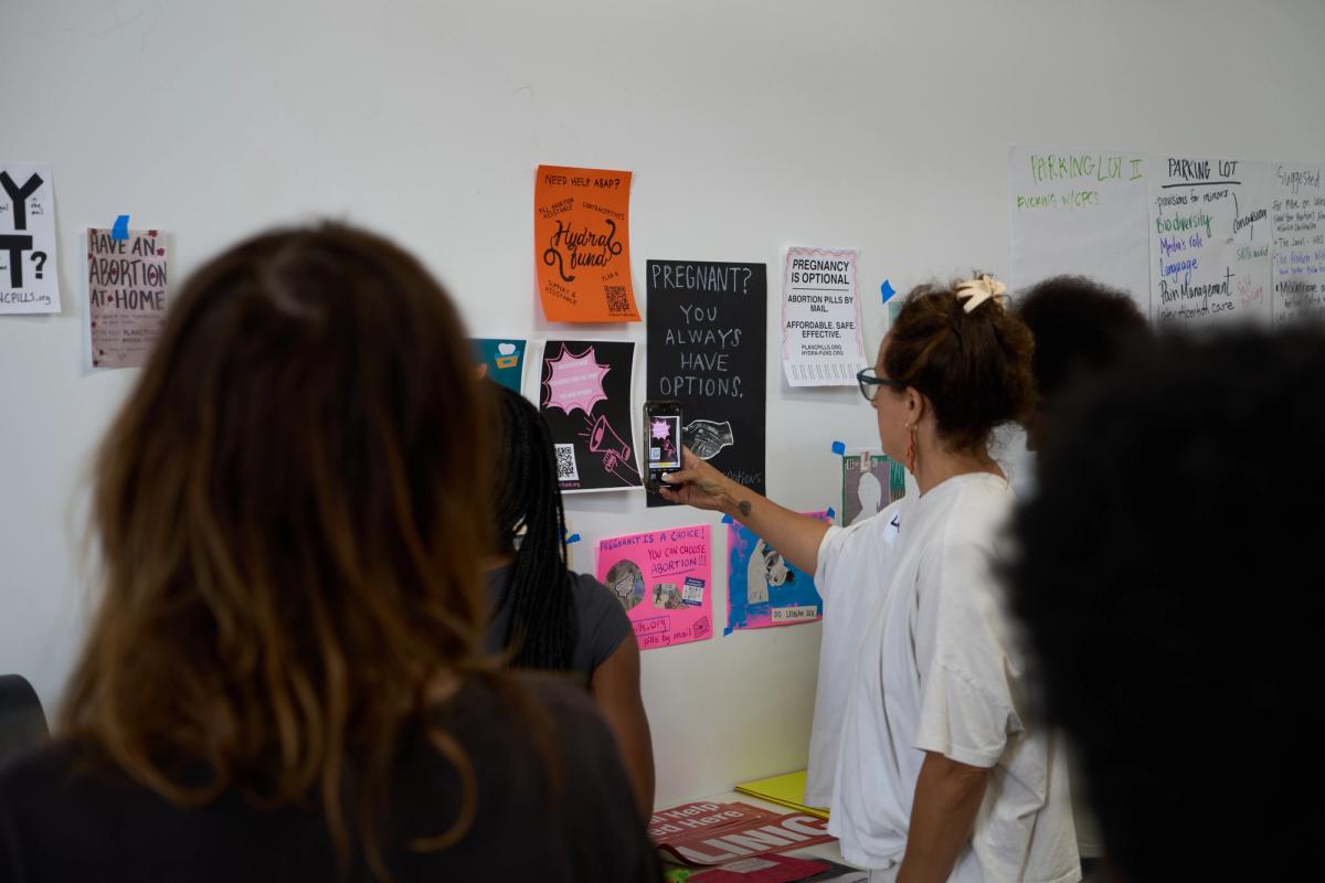 a group of women are standing in front of a wall with posters on it .