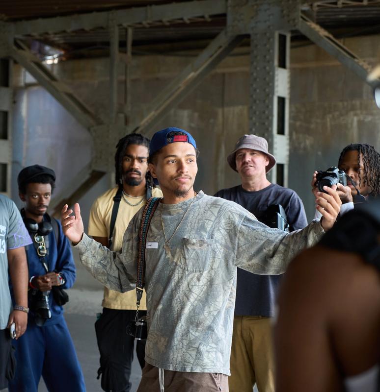 a group of men are standing around a man holding a camera .