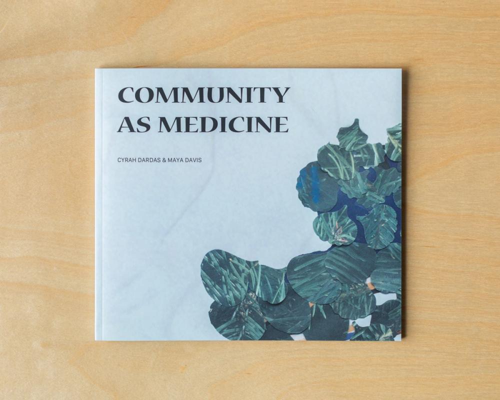 a book titled community as medicine is sitting on a wooden table .