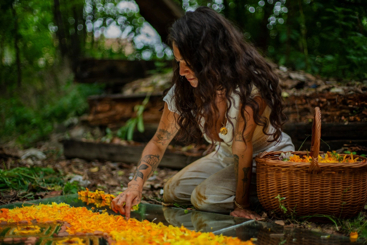 a woman kneeling down with a basket of flowers in front of her