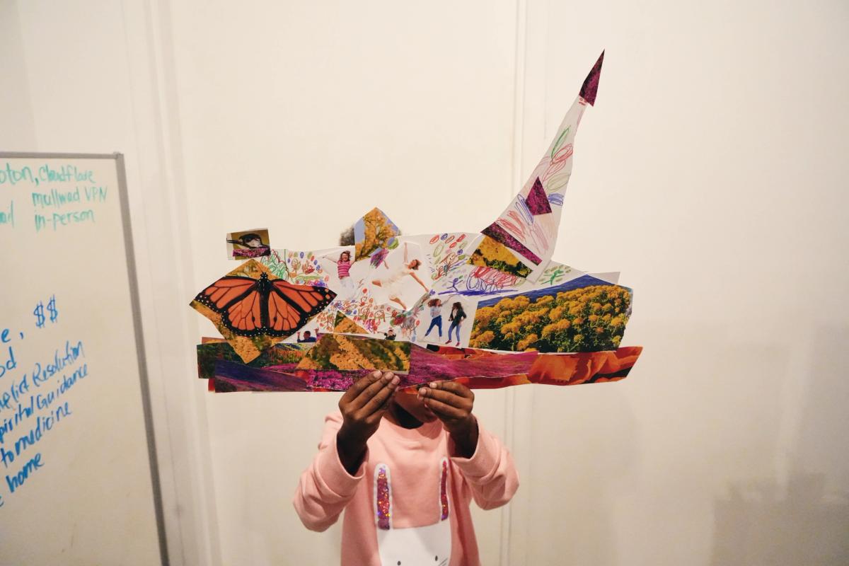 a little girl is holding a collage of pictures in front of her face .