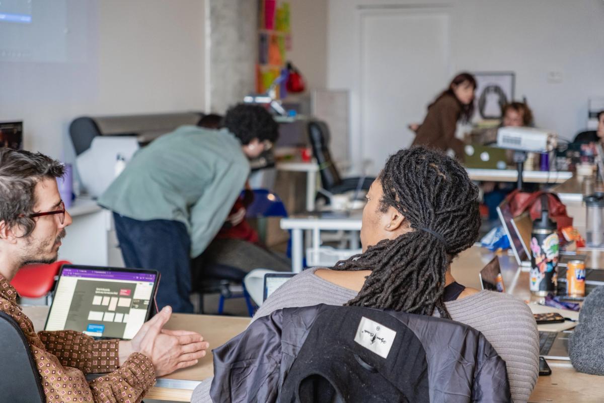 An active open-plan office with several people working and interacting.