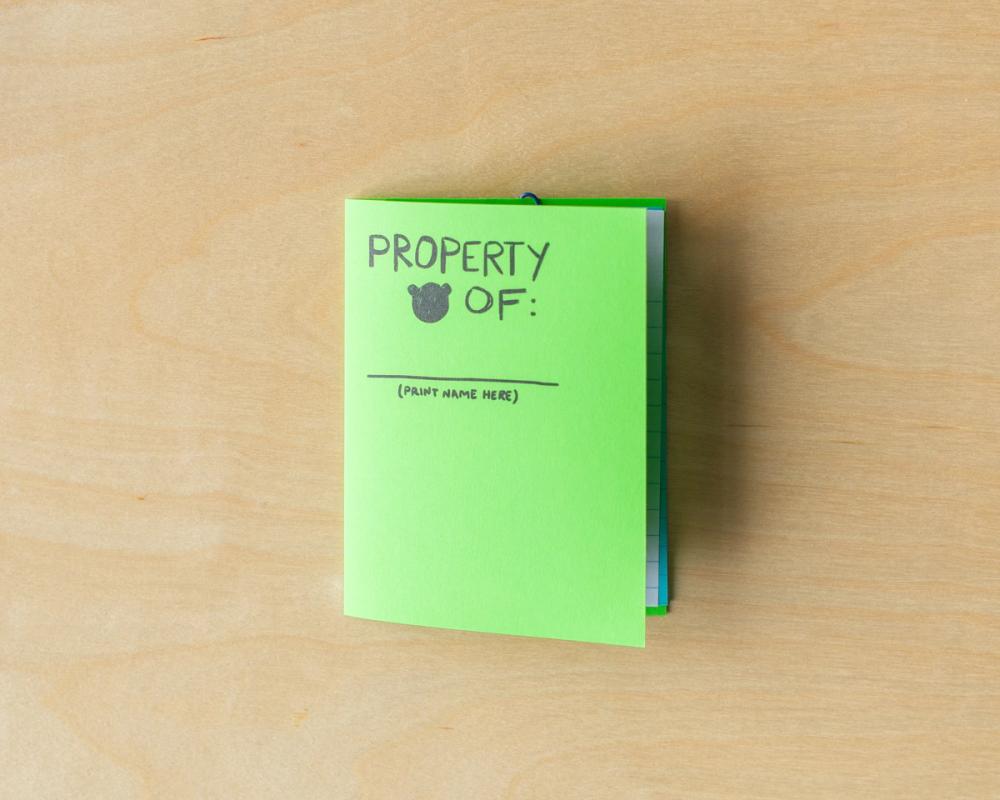 a green book titled property of is sitting on a wooden table