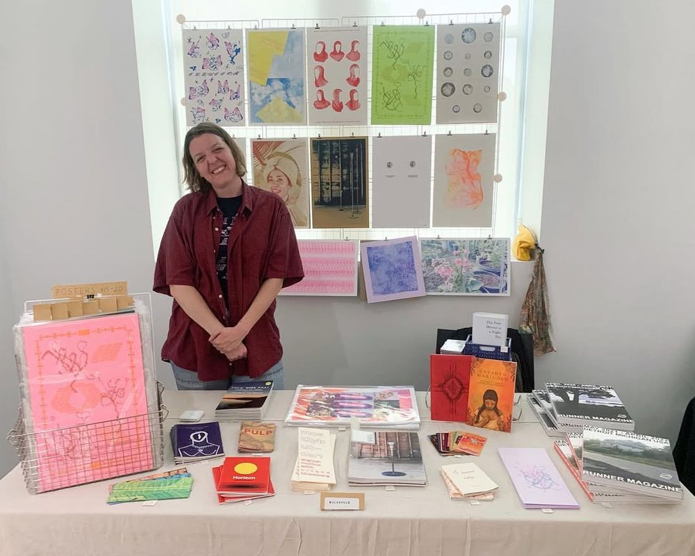 a woman is standing in front of a table filled with books .