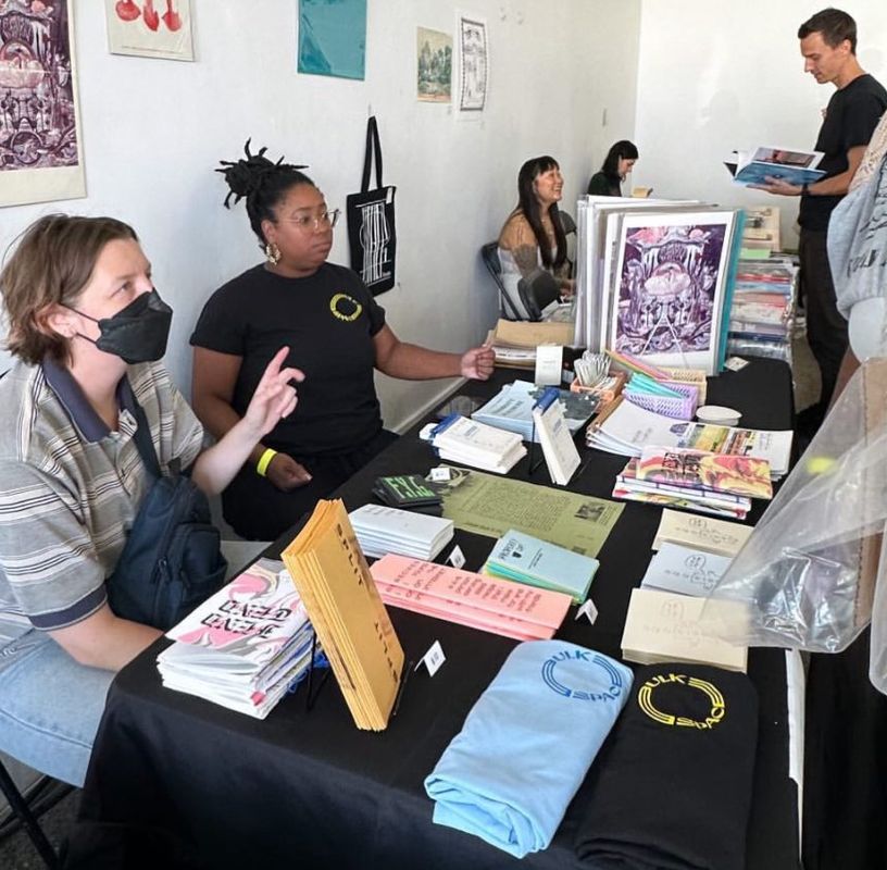 a group of people are sitting at a table with books on it .