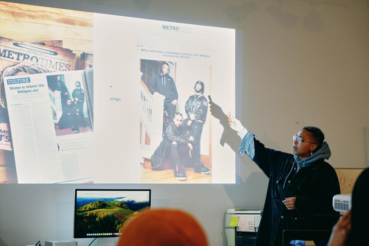 a woman is giving a presentation to a group of people in front of a projector screen .