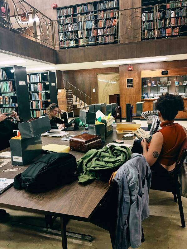 a woman sits at a table in a library looking at her phone