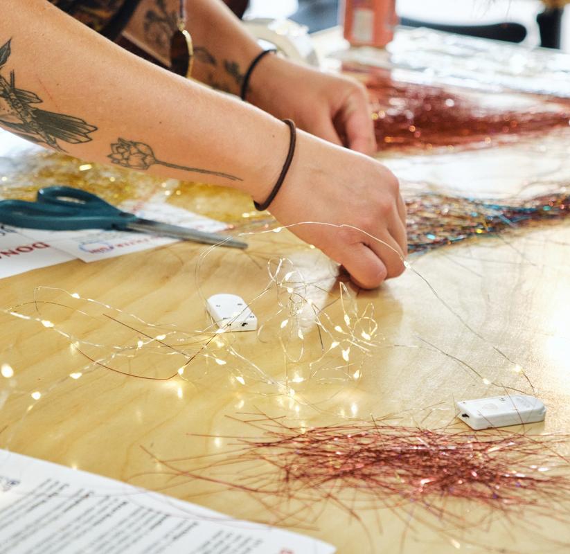 a woman is sitting at a table cutting tinsel with scissors .