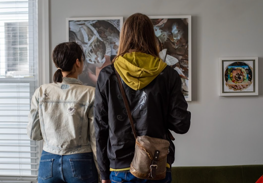 two women are looking at a painting on a wall
