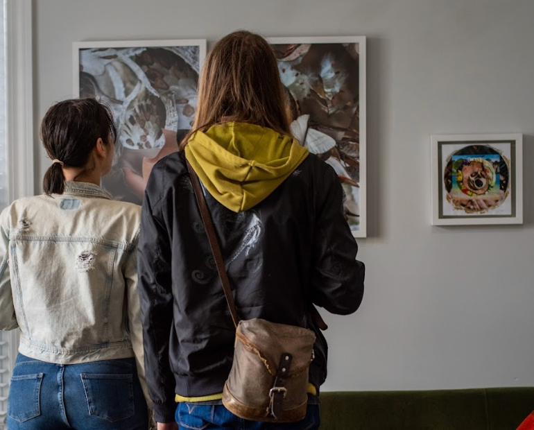 two women are looking at a painting on a wall