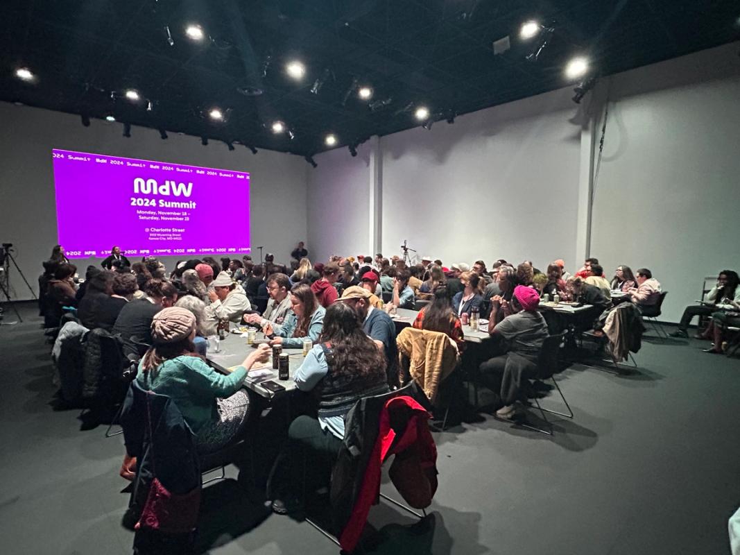 a large group of people are sitting at tables in a large room .