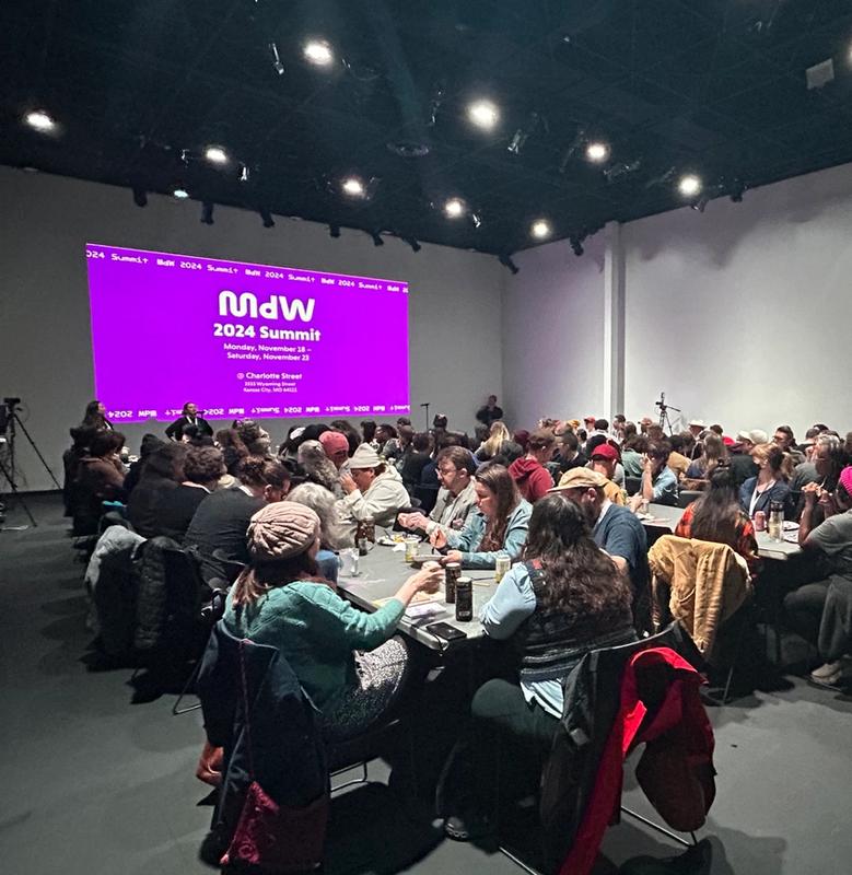 a large group of people are sitting at tables in a large room .