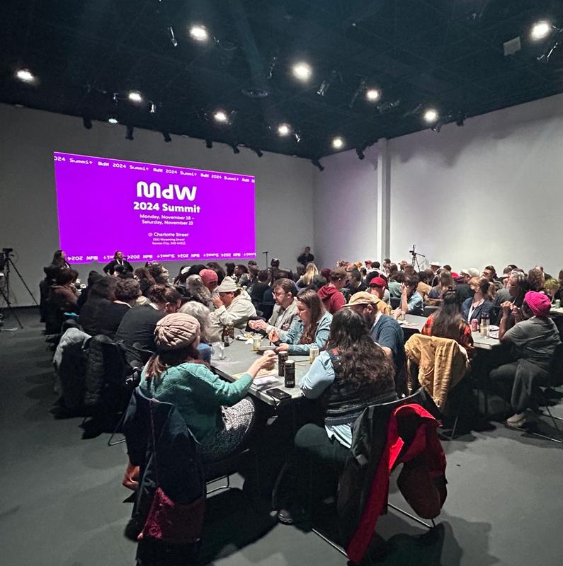 a large group of people are sitting at tables in a large room .