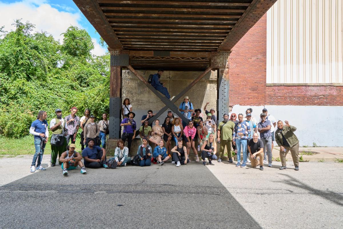 a group of people are posing for a picture under a bridge .