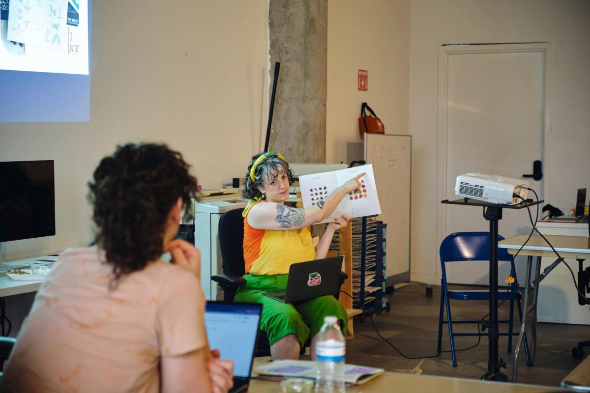 a woman is sitting at a table holding a piece of paper while a man looks on .