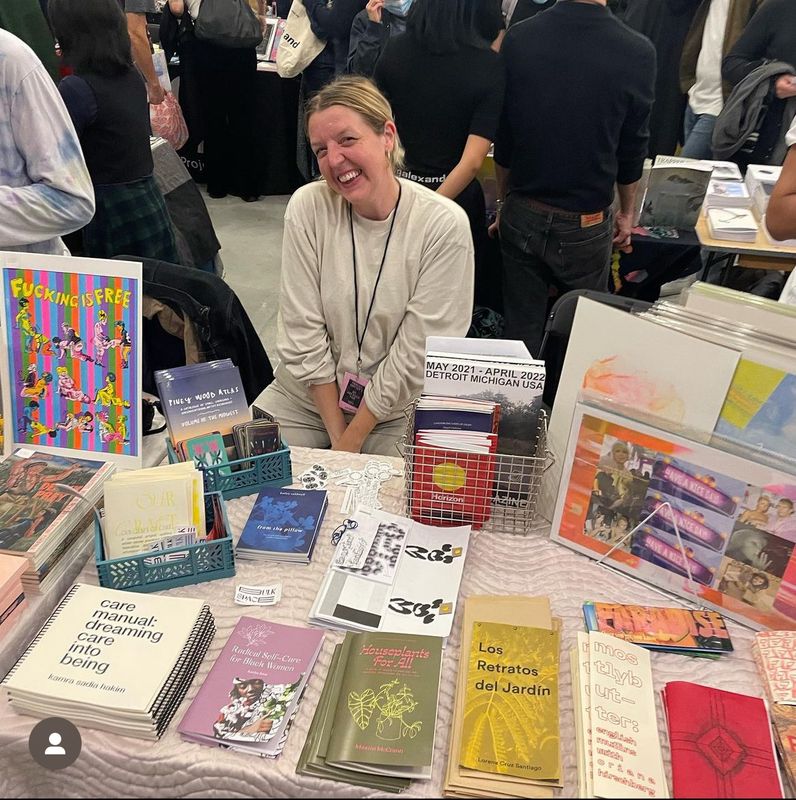 a woman is sitting at a table with a bunch of books on it .