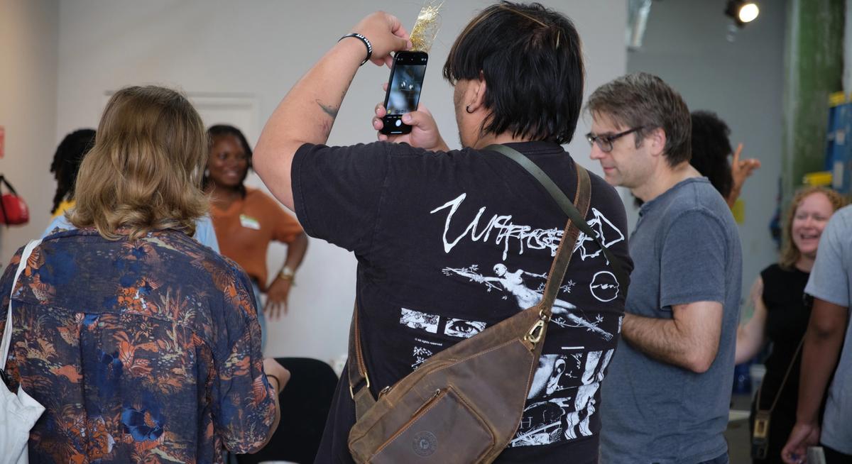a man is taking a picture of a group of people with a cell phone .
