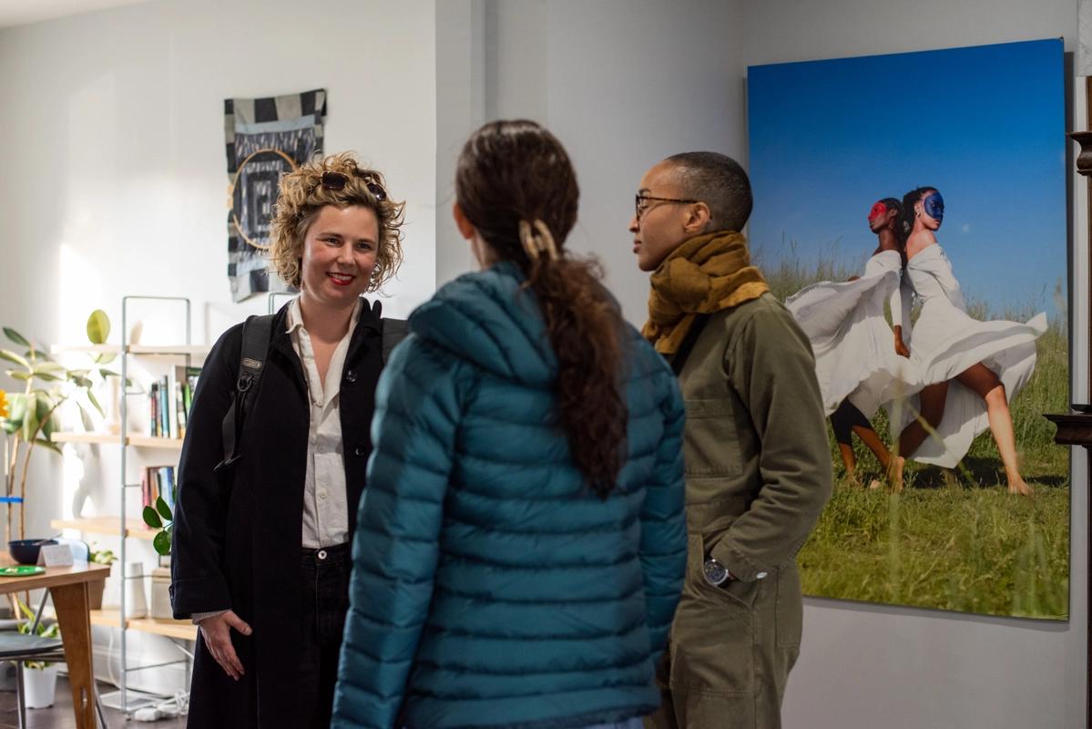 a group of people are standing in a room talking to each other .