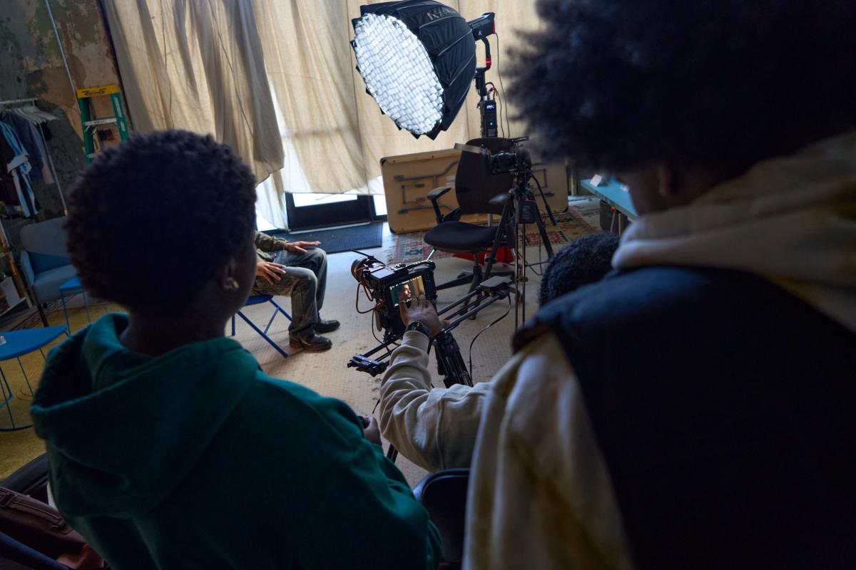 a group of young men are sitting in front of a camera in a room .