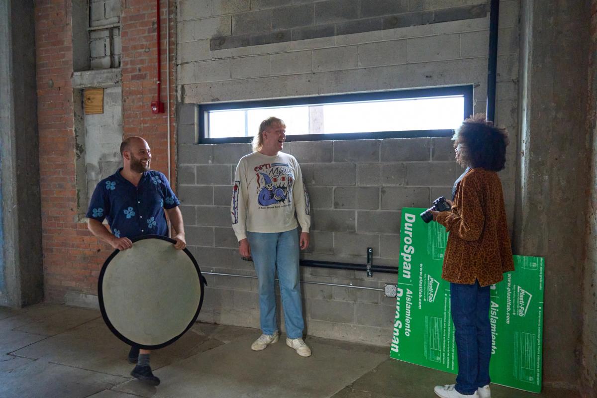 a group of people are standing next to each other in a room in front of a window .