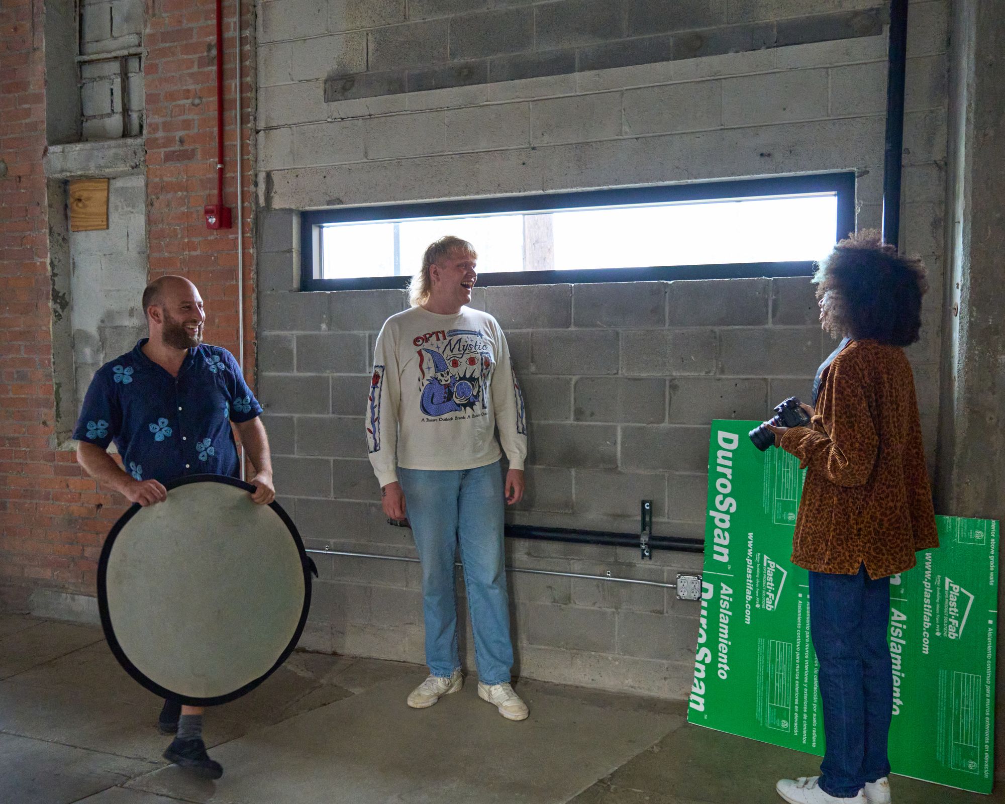 a group of people are standing next to each other in a room in front of a window .