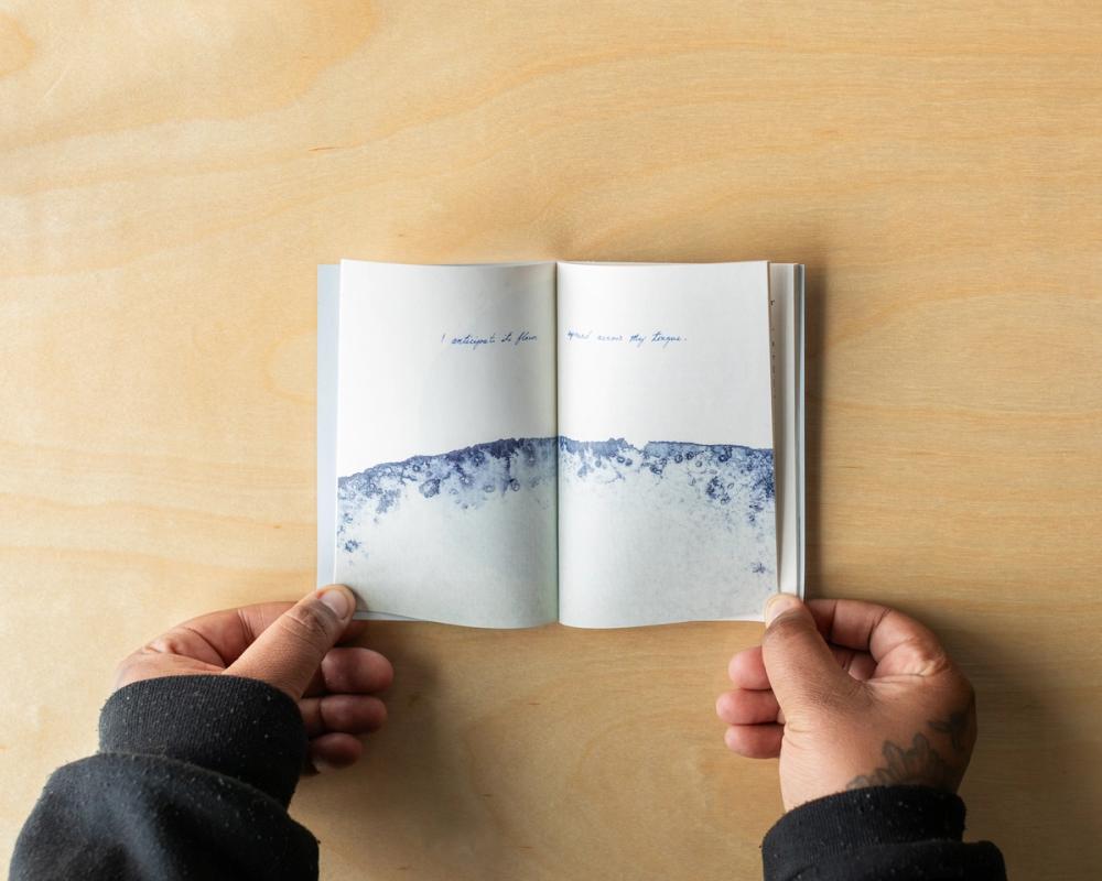 a person is holding a book in their hands on a wooden table .