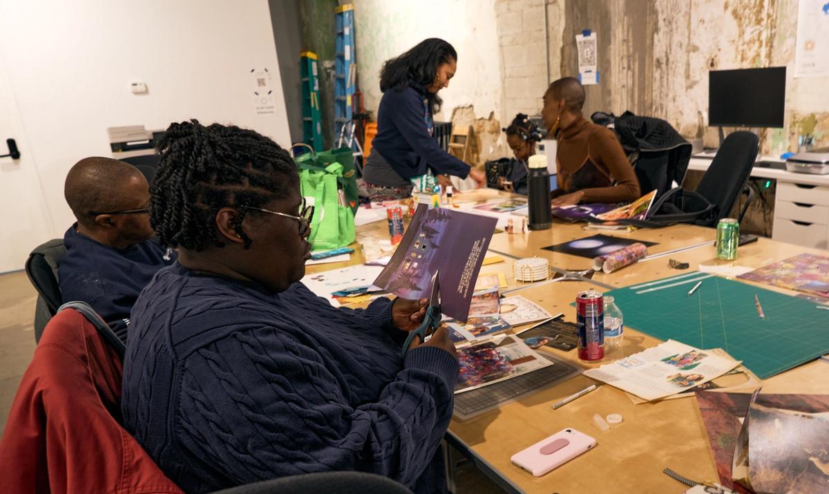 a group of people are sitting around a table making art .