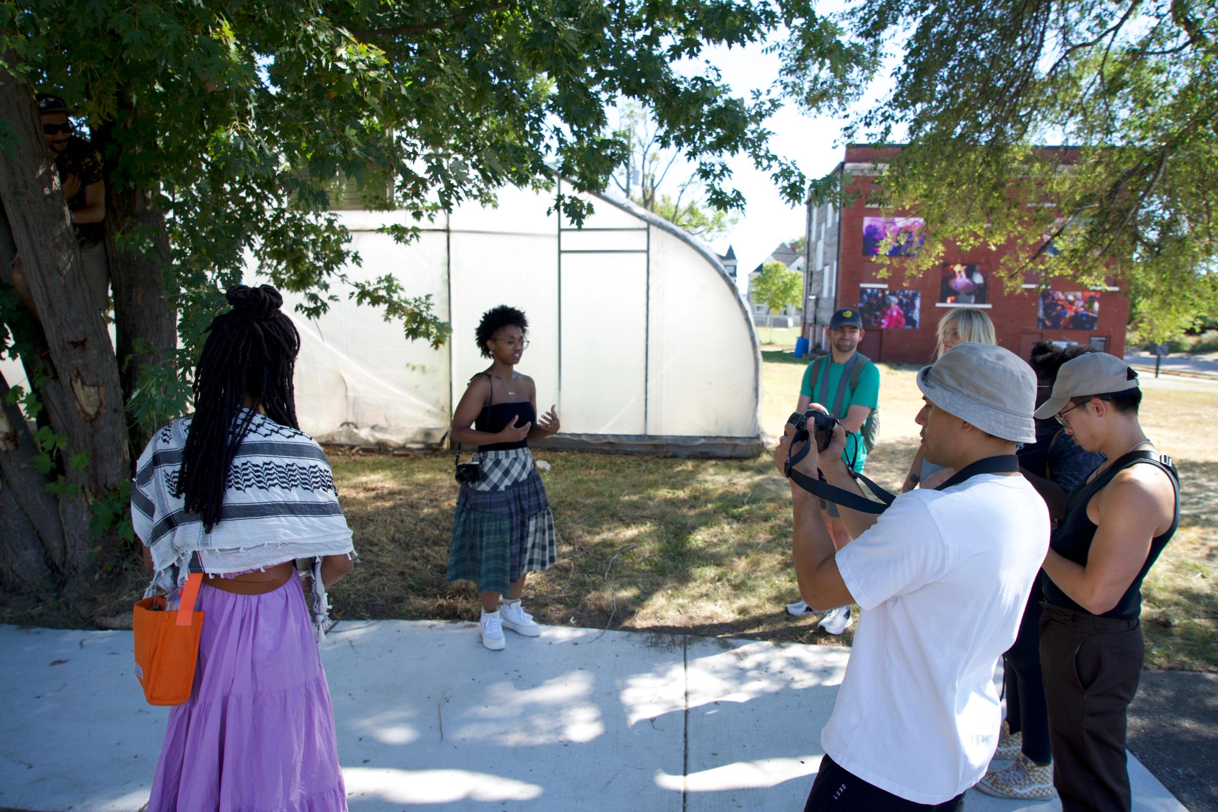 a group of people are standing on a sidewalk in front of a greenhouse .