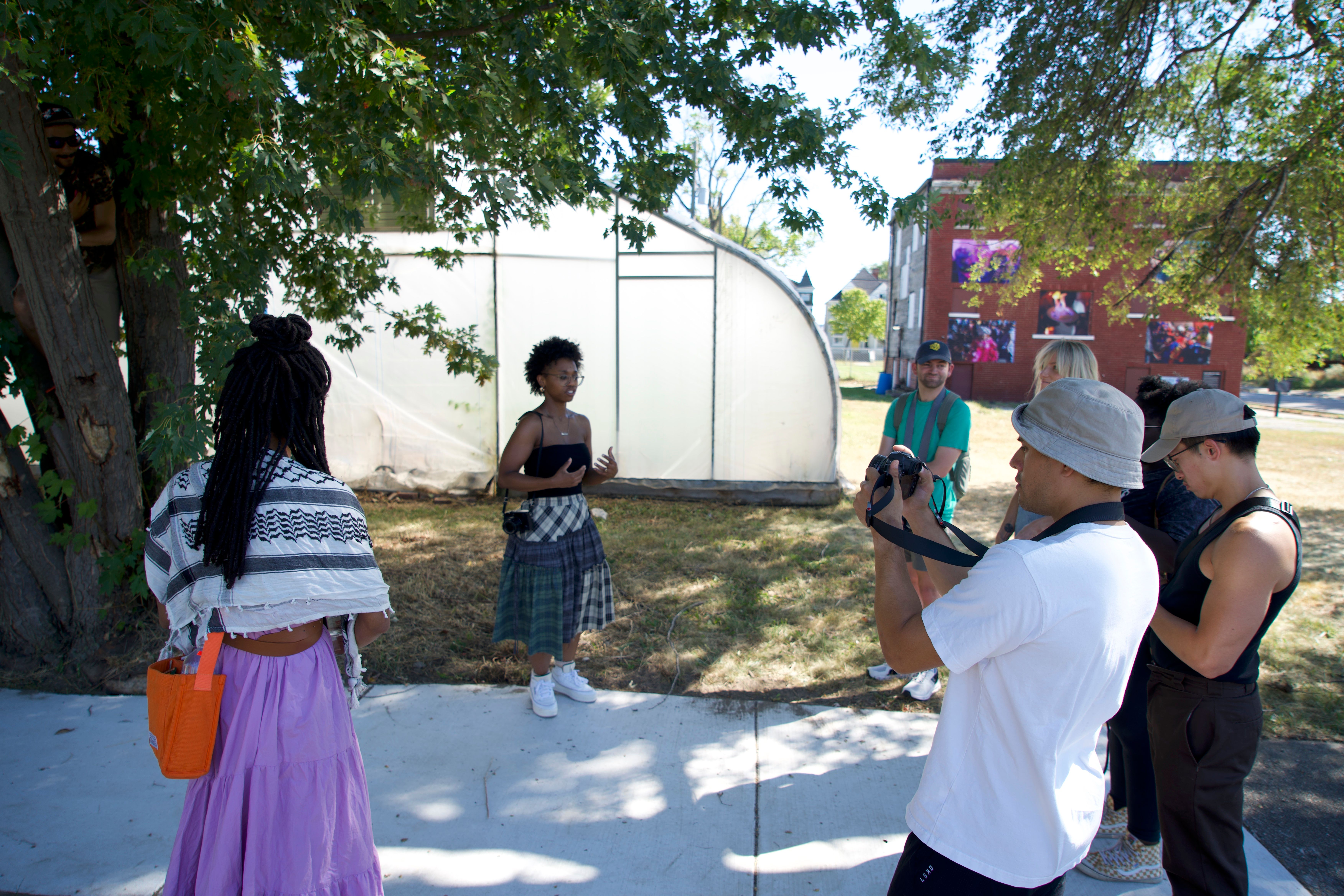 a group of people are standing on a sidewalk in front of a greenhouse .