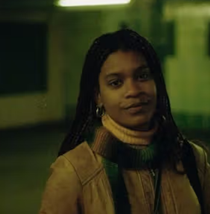 a woman wearing a scarf and a jacket is standing in a dark room