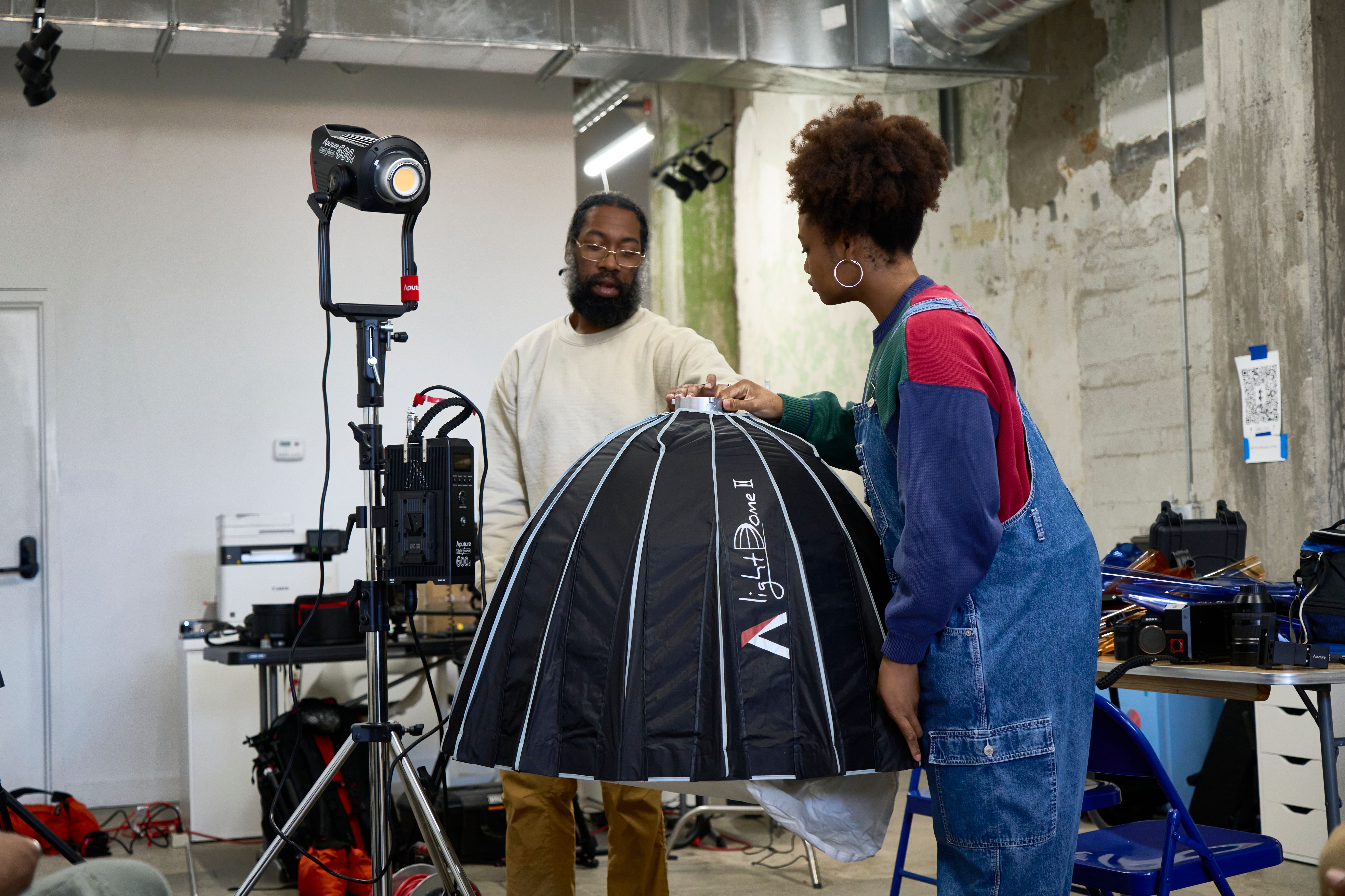 a man and a woman are standing next to each other in a room looking at a light .
