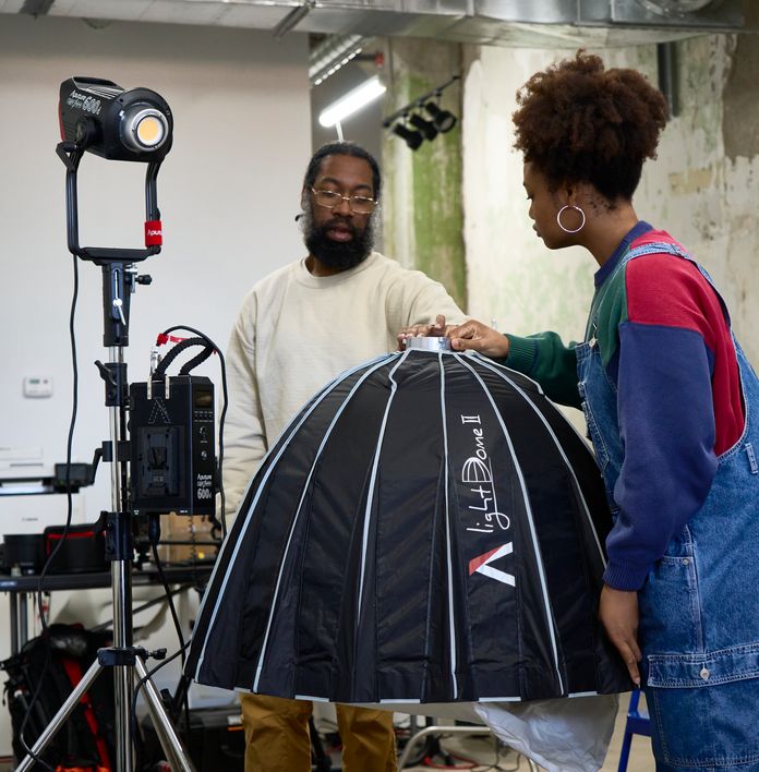 a man and a woman are standing next to each other in a room looking at a light .