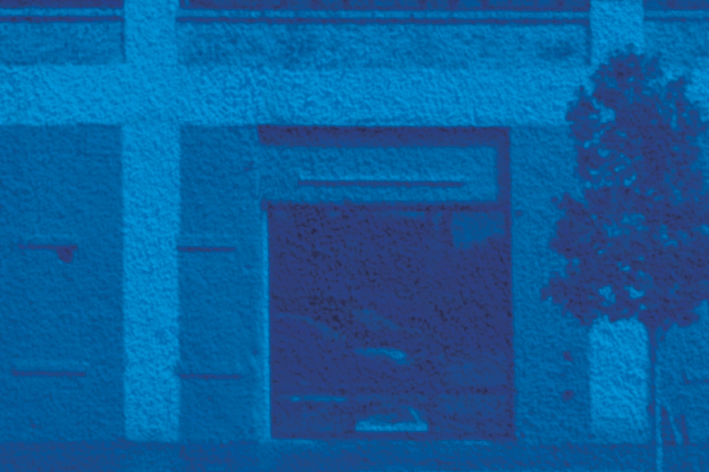 A textured, blue-monochrome image of a three-story building with grid windows, ground-floor garage doors, and a small tree on the sidewalk.
