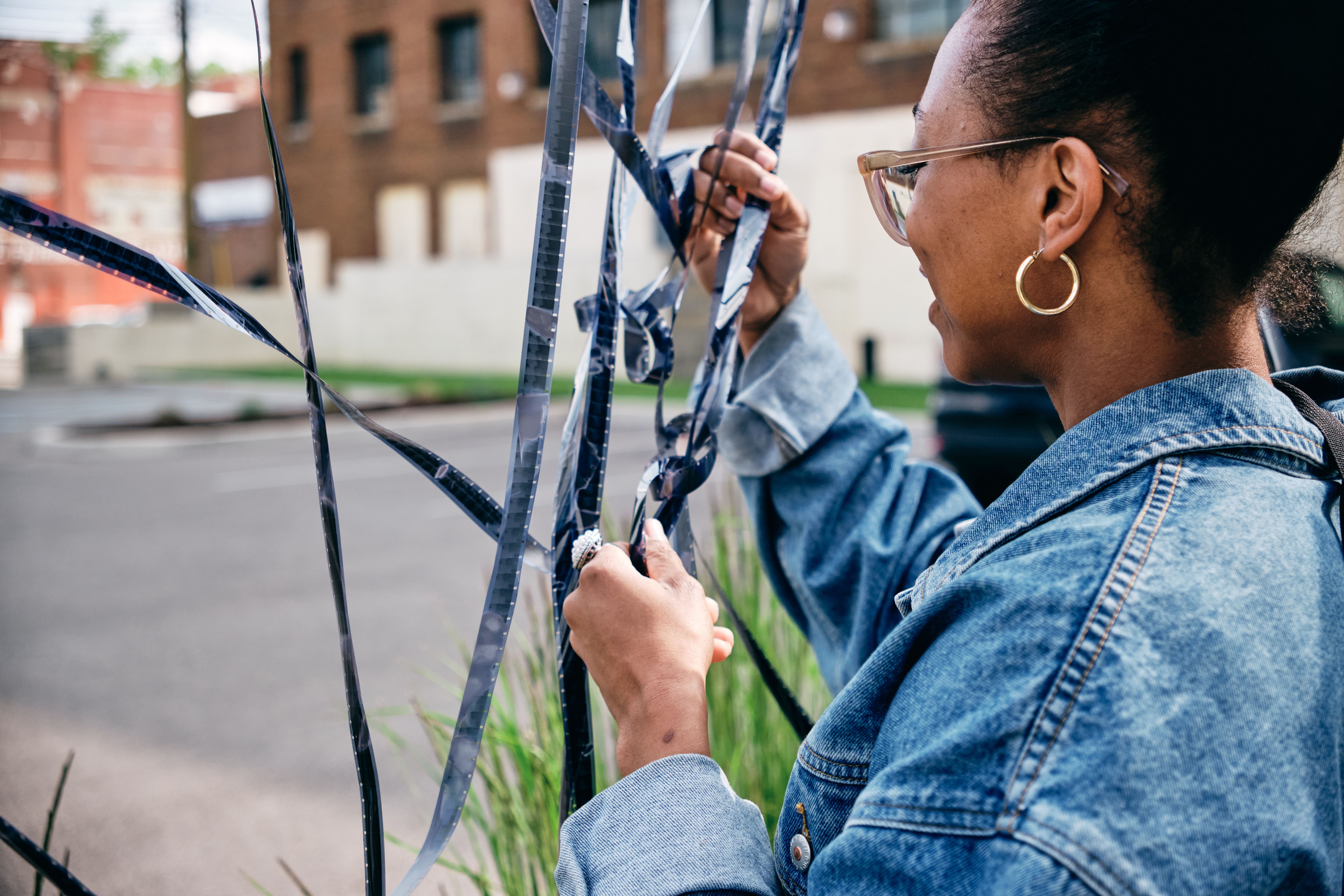 a woman in a denim jacket is holding a roll of film .