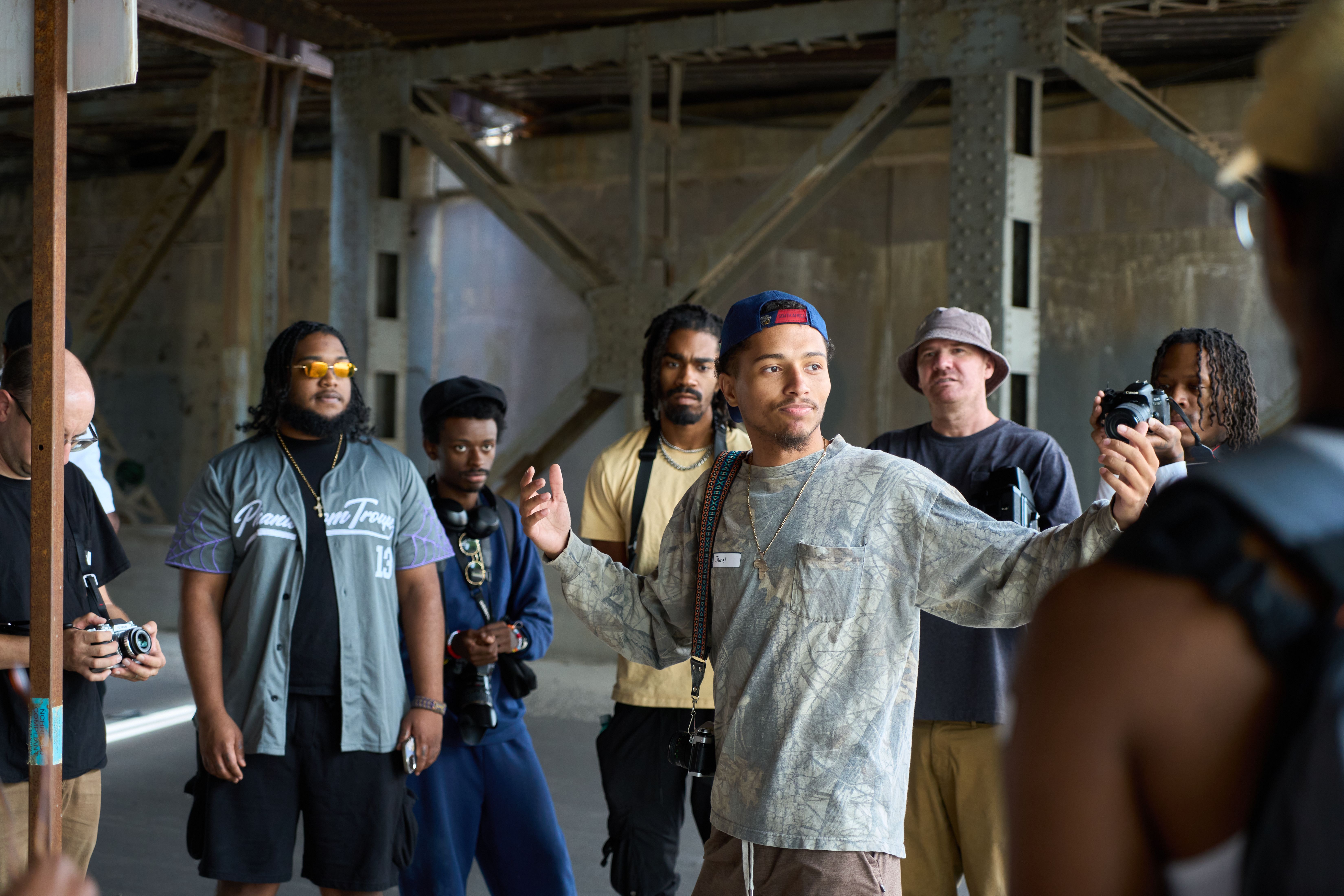 a group of men are standing around a man holding a camera .