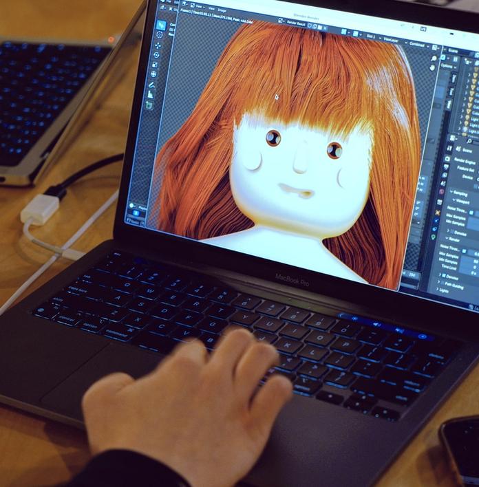 a person is typing on a laptop computer with a doll on the screen .
