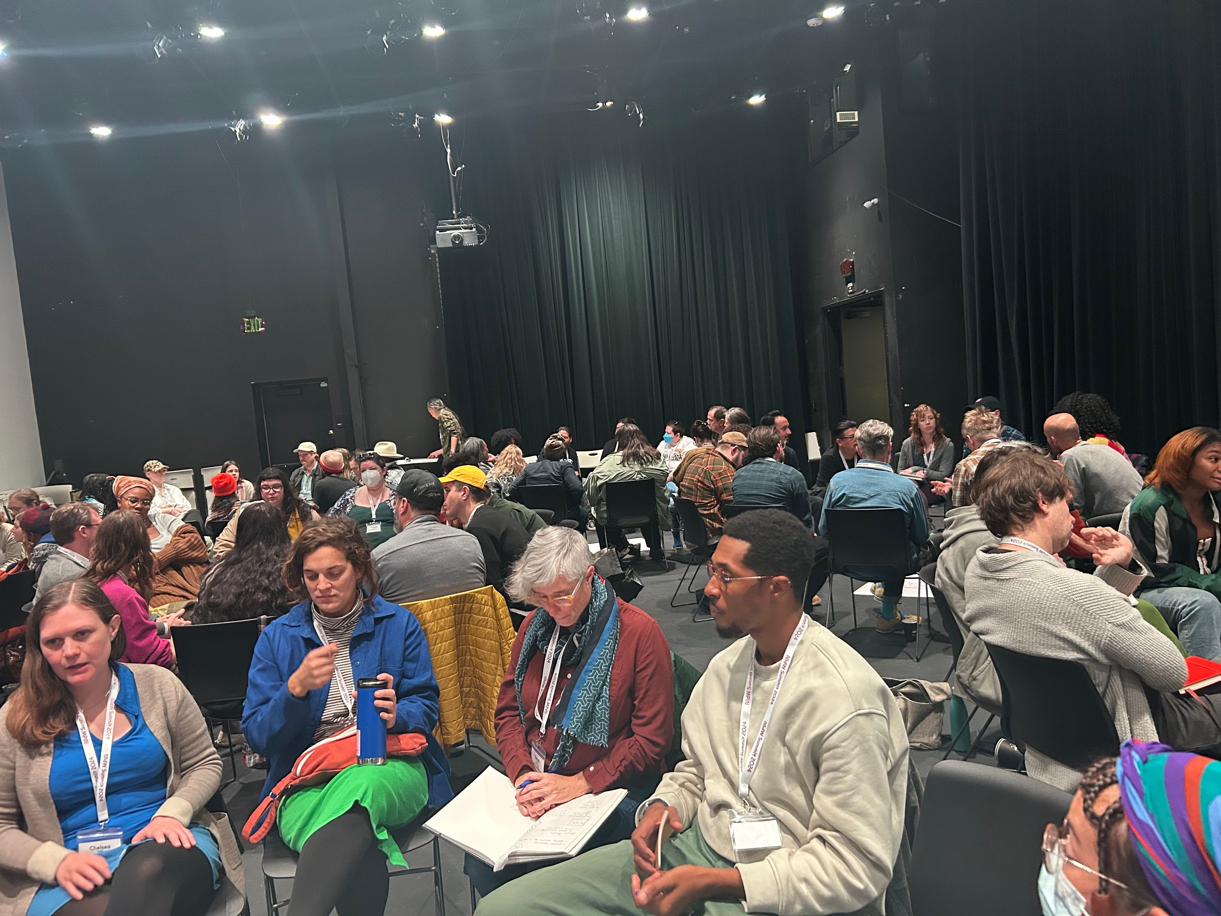 a large group of people are sitting in a large auditorium .