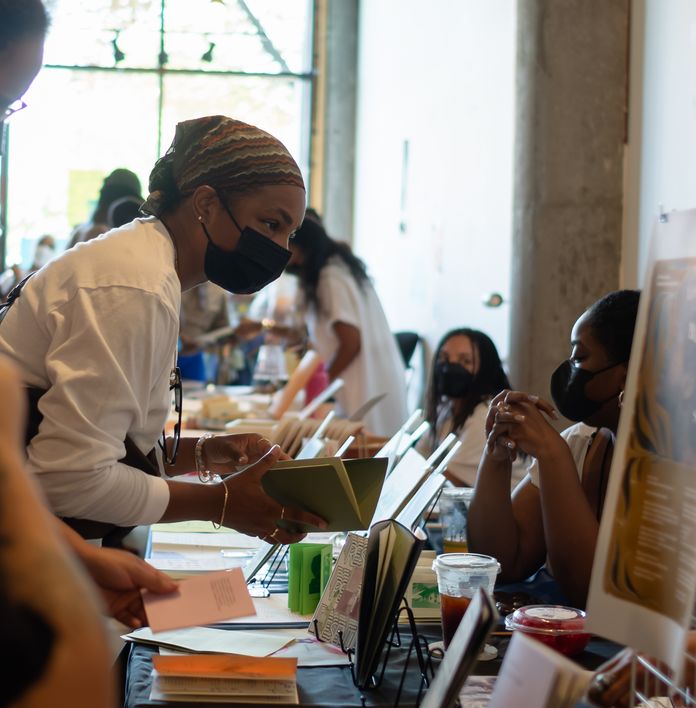 a woman wearing a mask is standing at a table with other people .