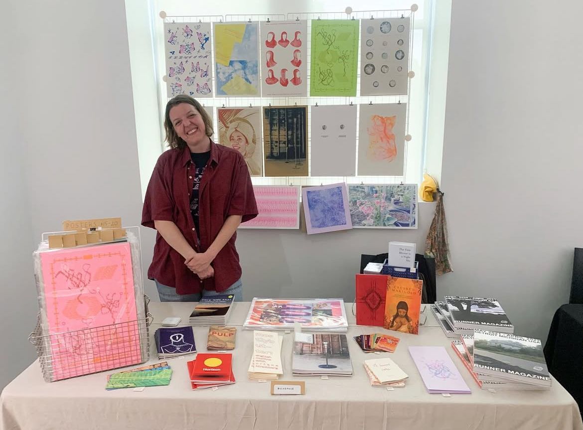 a woman is standing in front of a table filled with books .
