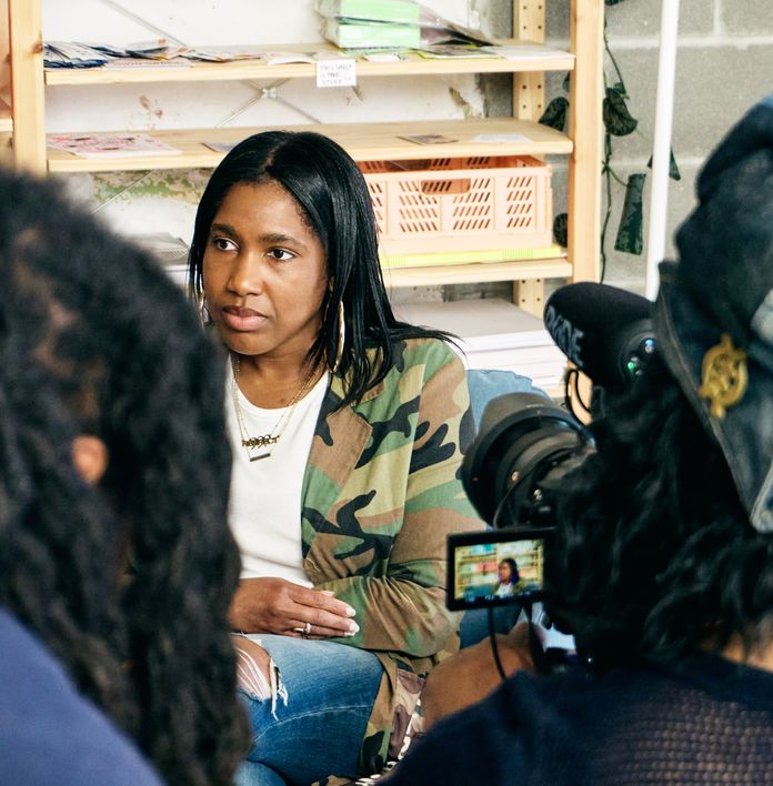 a woman is sitting in front of a camera talking to another woman .