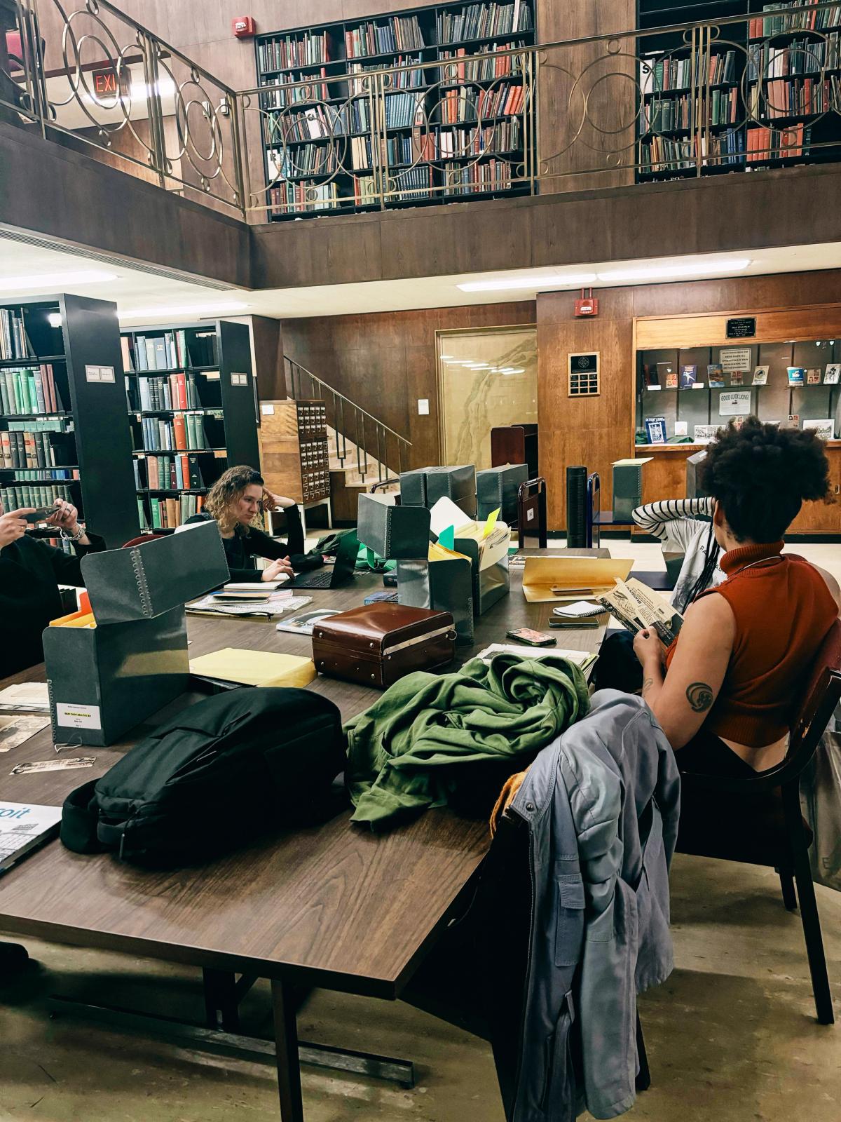 a woman sits at a table in a library looking at her phone
