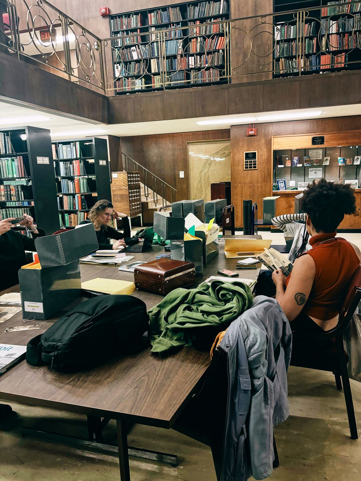 a woman sits at a table in a library looking at her phone