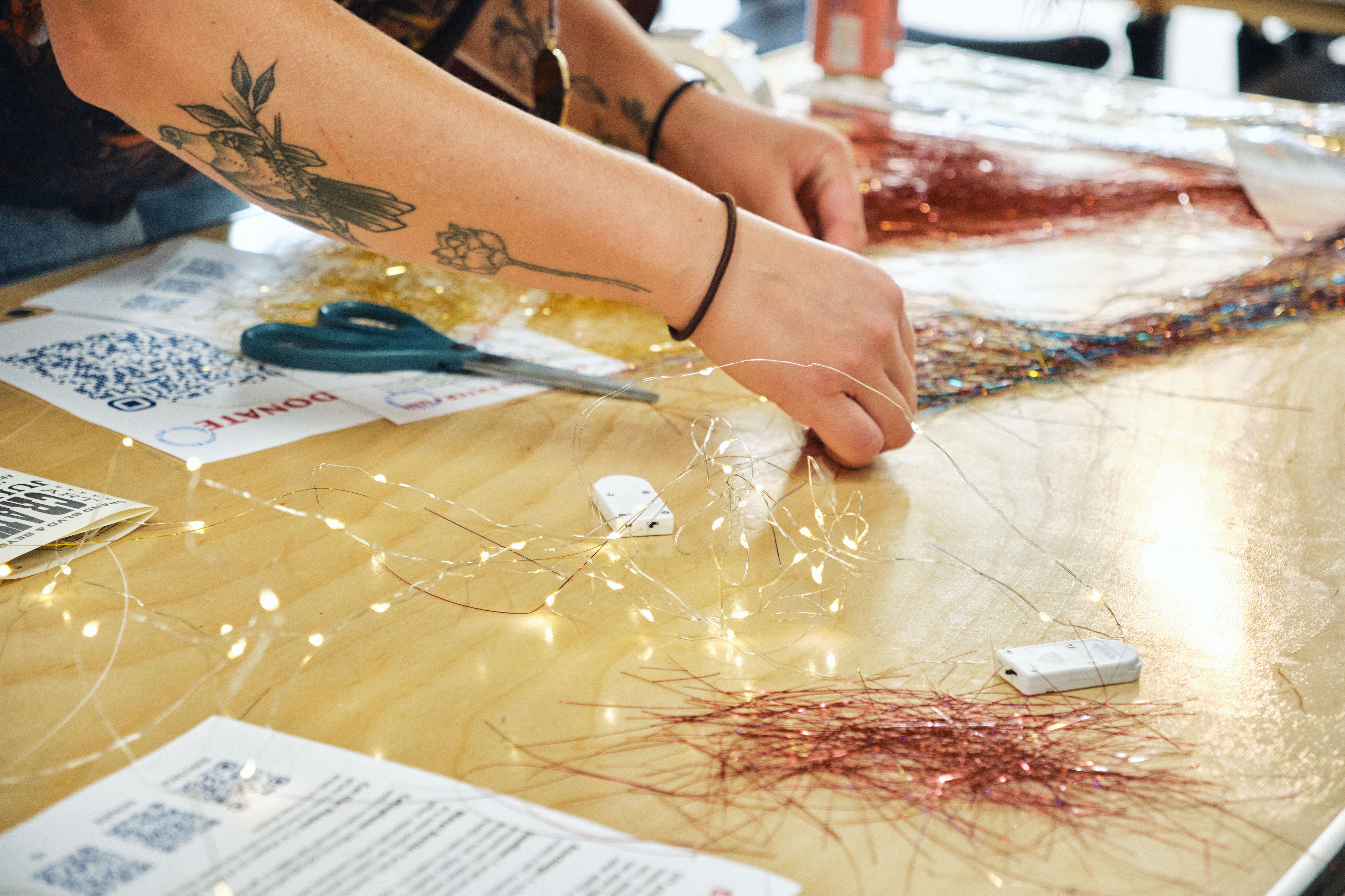 a woman is sitting at a table cutting tinsel with scissors .