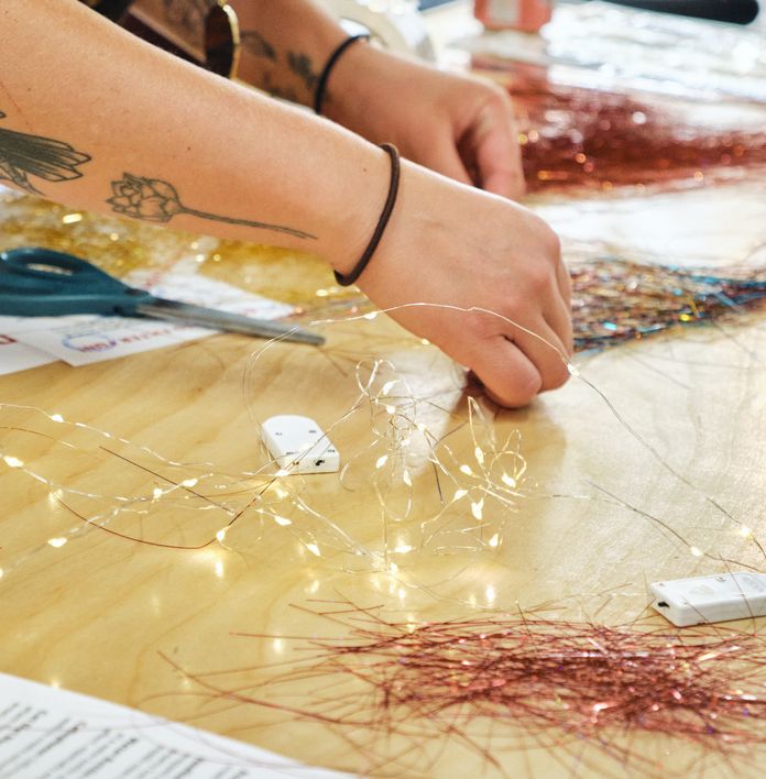 a woman is sitting at a table cutting tinsel with scissors .