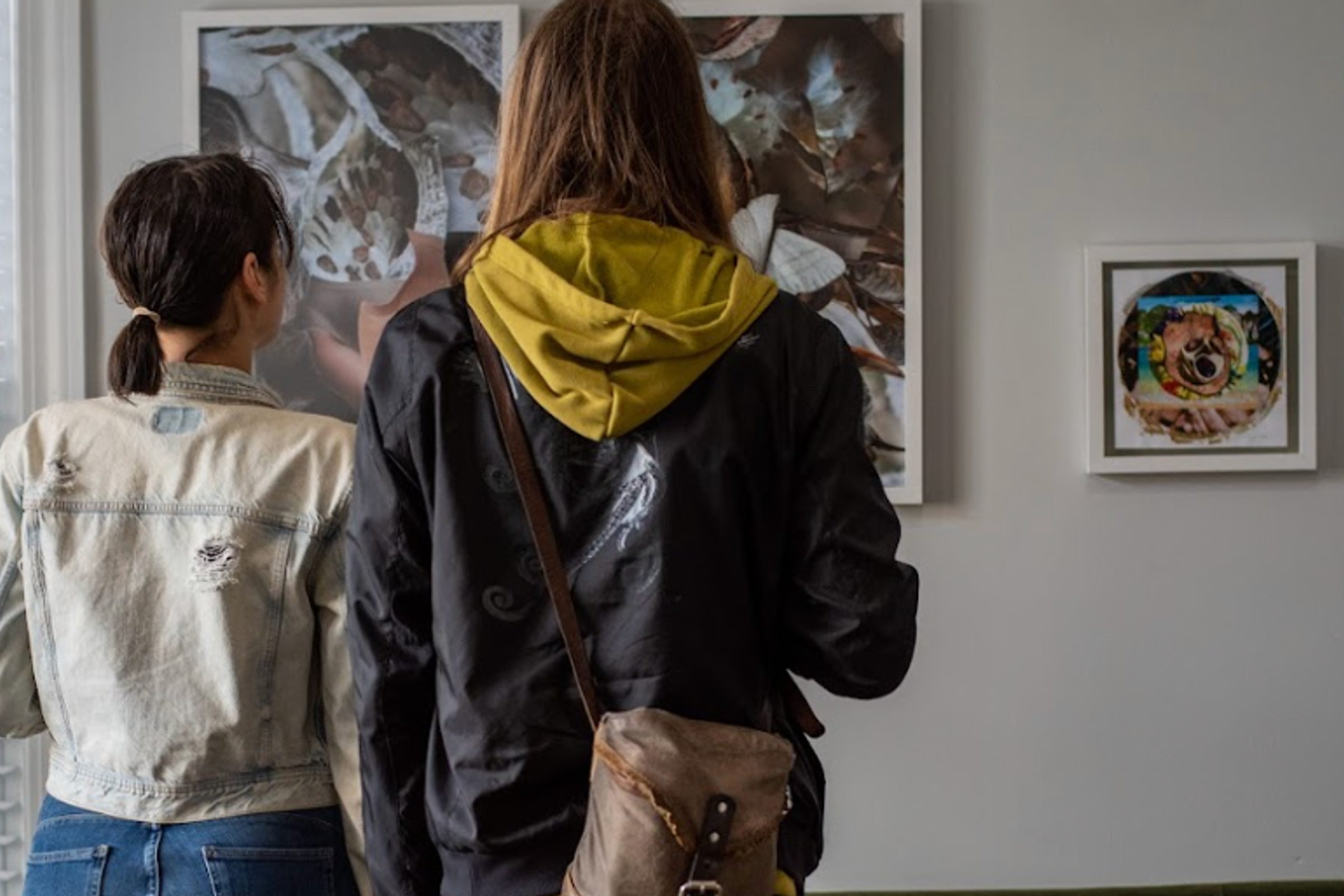 two women are looking at a painting on a wall