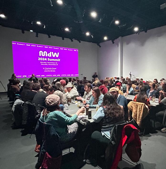 a large group of people are sitting at tables in a large room .