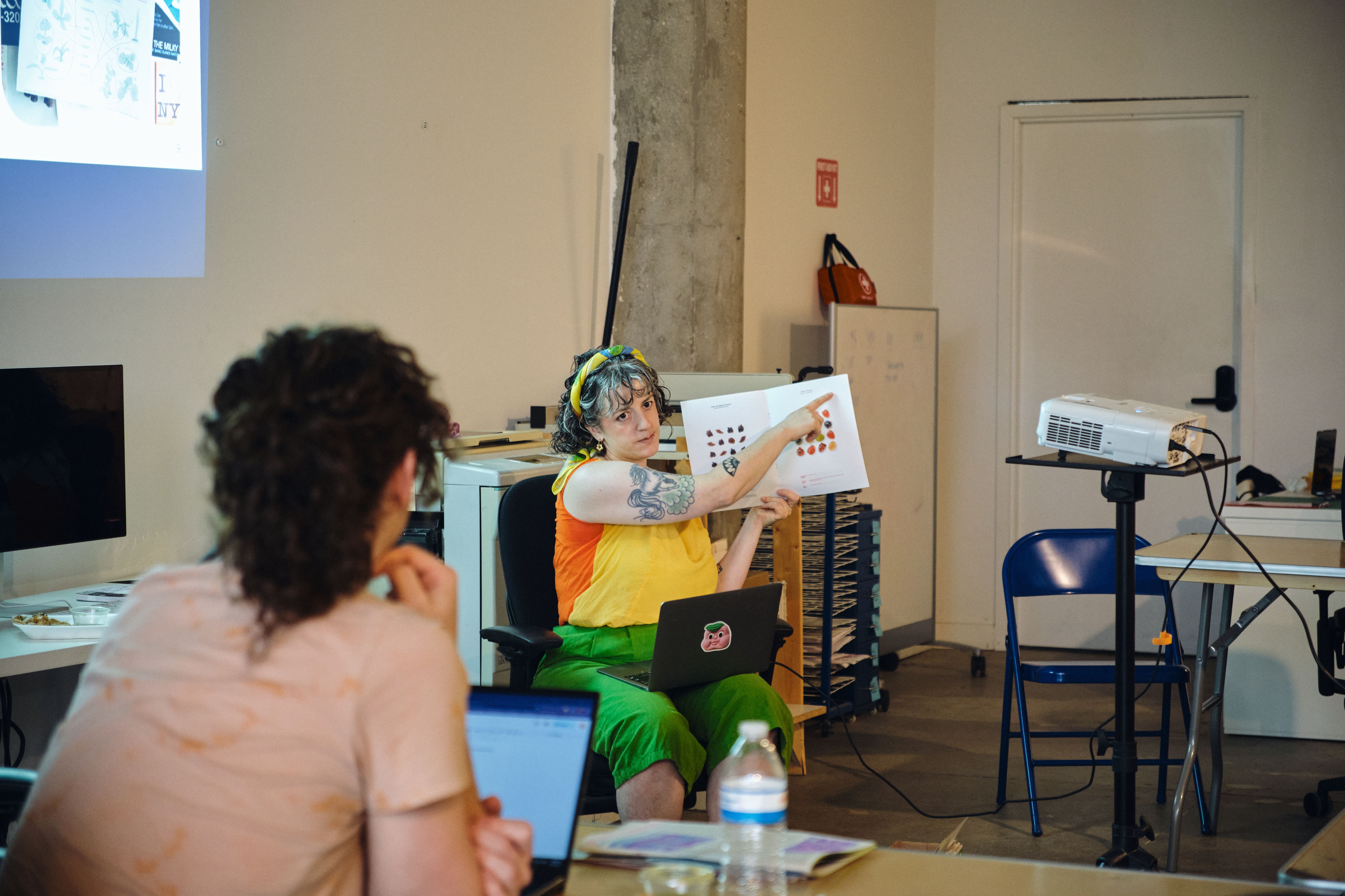 a woman is sitting at a table holding a piece of paper while a man looks on .
