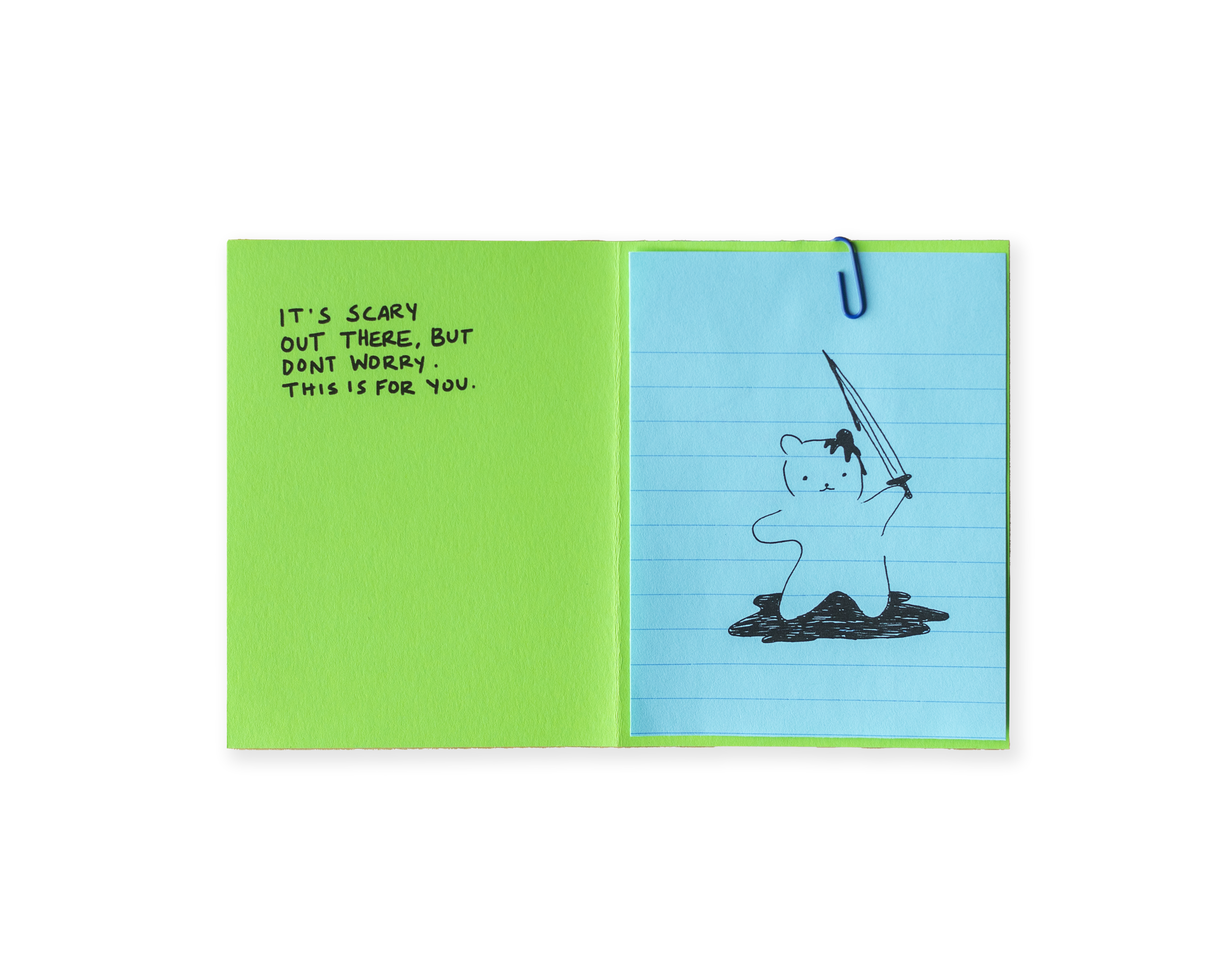 A lime green paper with partial black text folded over light blue lined paper with a partial black drawing.