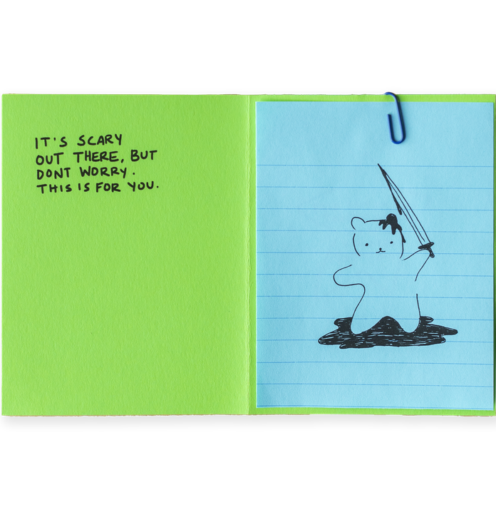 A lime green paper with partial black text folded over light blue lined paper with a partial black drawing.