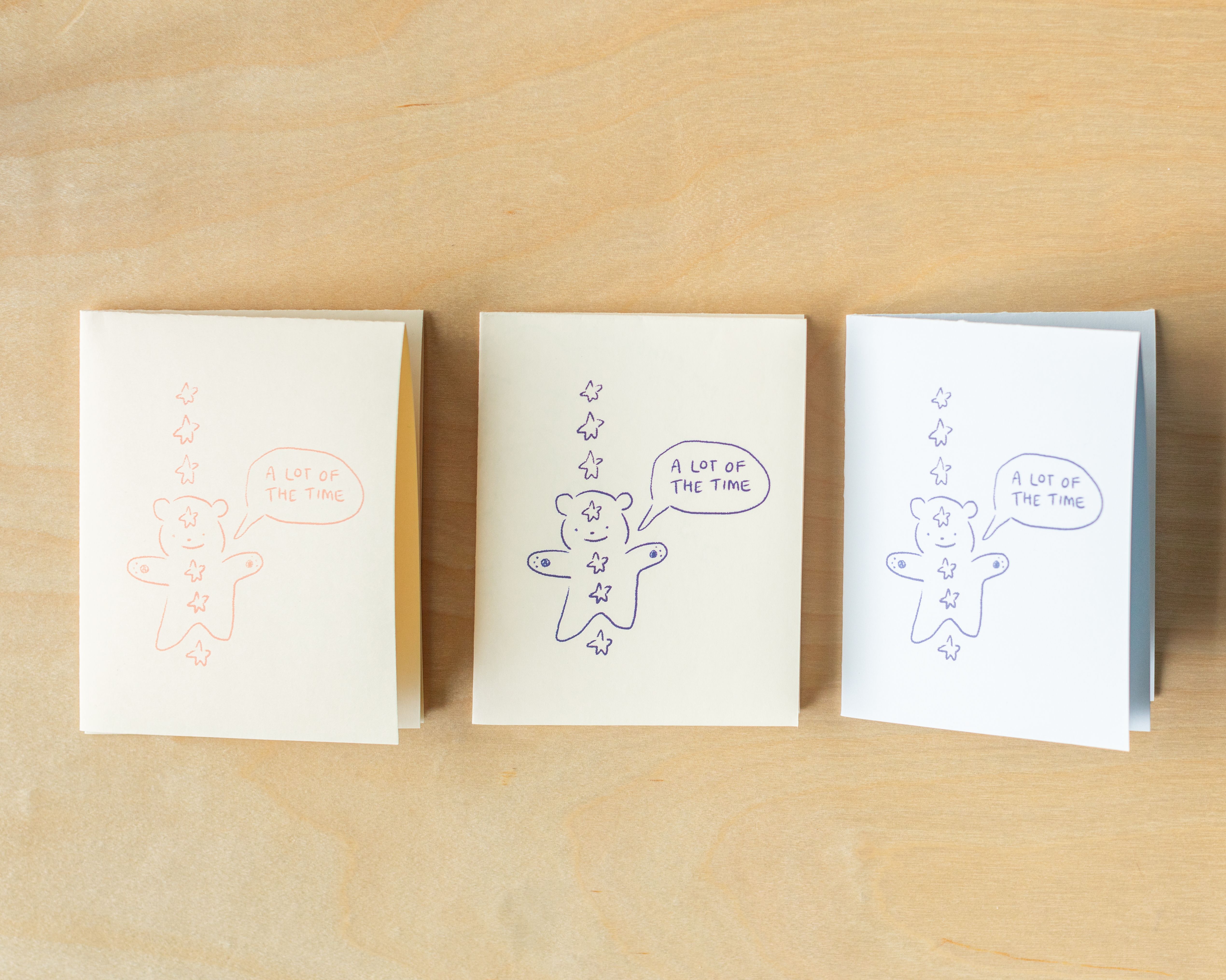 three cards with gingerbread men on them are sitting on a wooden table .
